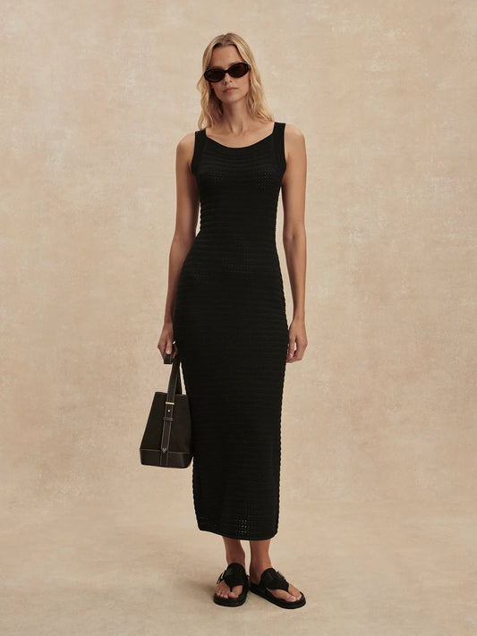 Woman wearing a black sleeveless dress against a beige background