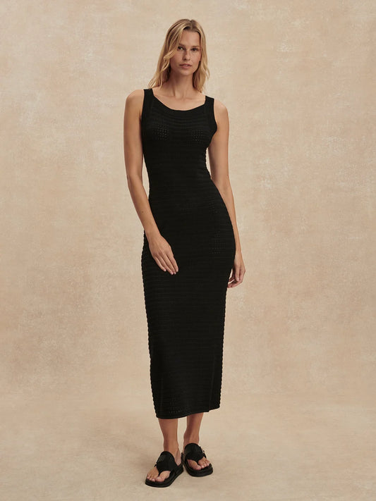 Woman wearing a black sleeveless dress against a beige background